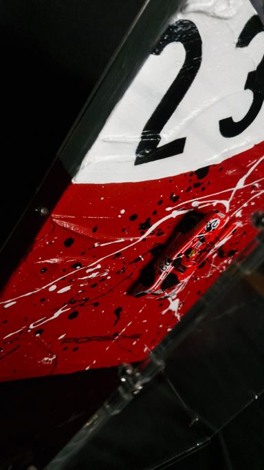 Zahl 23 auf einer rot-weißen Oberfläche mit Zweigen und Kratzern.